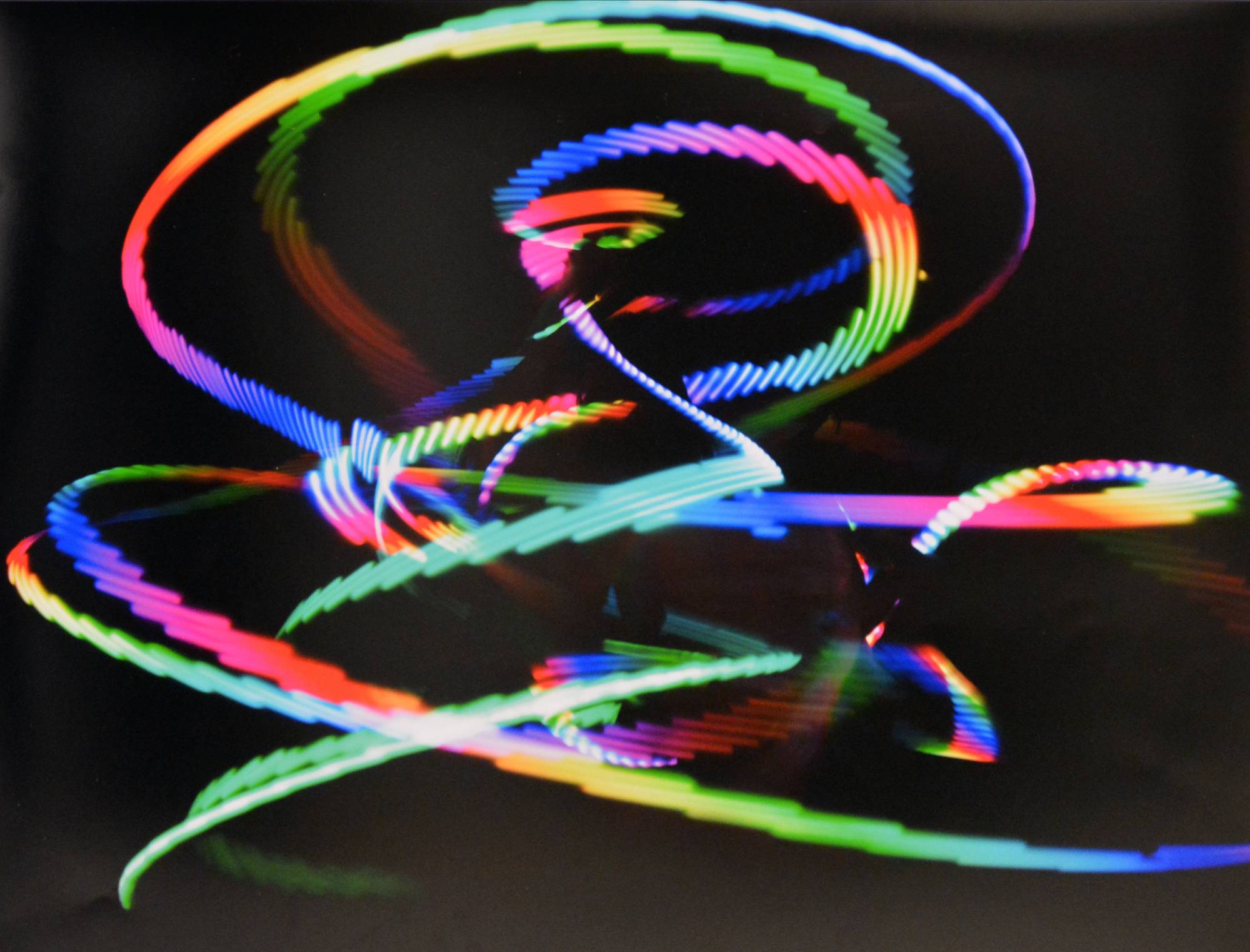 black background with rainbow light trails swirling in circular design